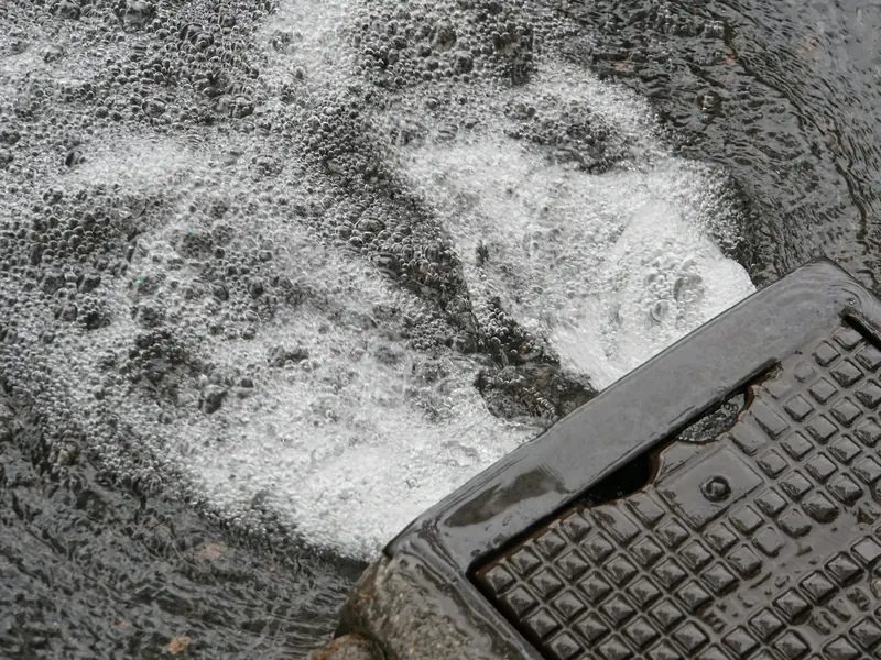 Foamy wash water running across concrete towards a drain