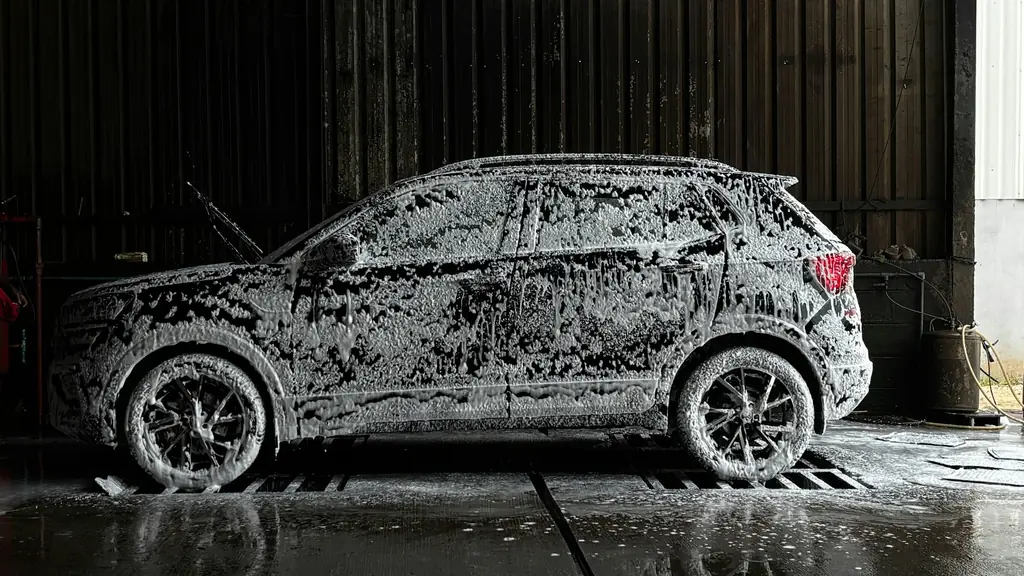 An SUV covered in thick wash foam, ready to be rinsed