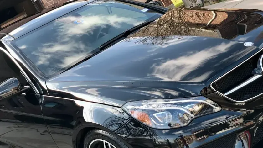 Clouds reflected in the hood of a black sedan