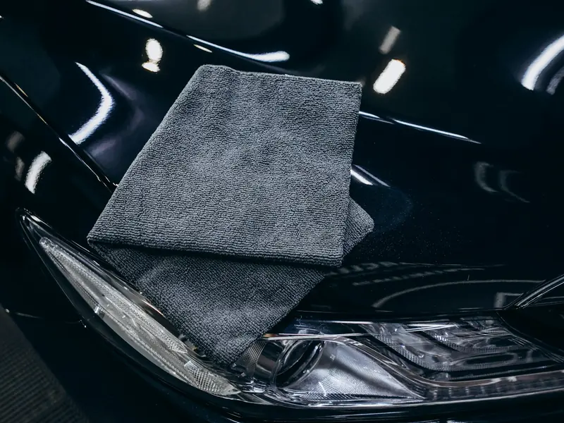 A grey microfiber towel resting on a freshly finished dark hood